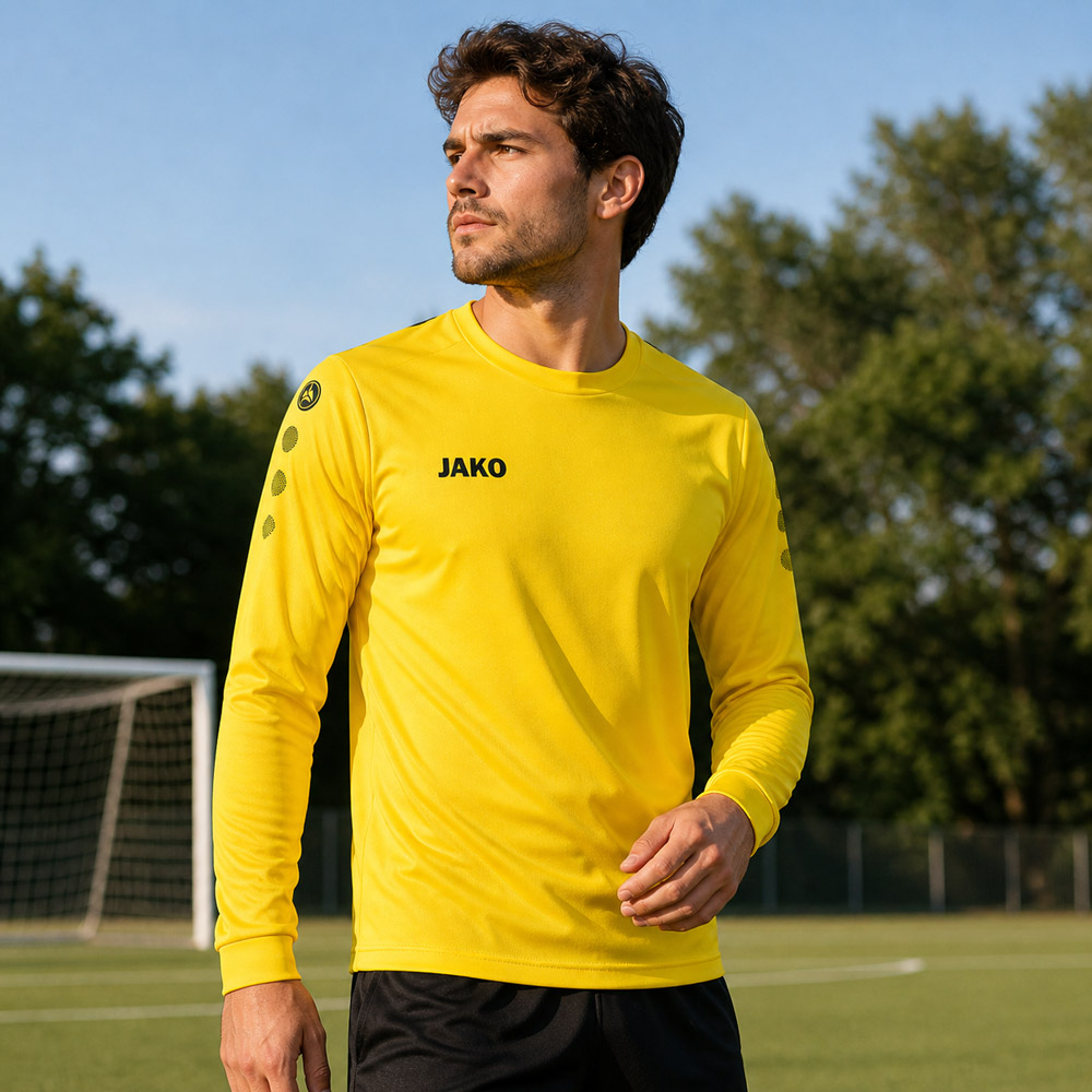 Mann auf Fussballplatz trägt gelbes JAKO Team Trikot mit langen Ärmeln